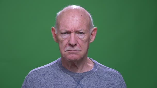 Κοντινό γύρισμα του παλιού καυκάσιου άντρα που ενοχλείται και απογοητεύεται κοιτάζοντας την κάμερα με φόντο απομονωμένο στο πράσινο — Αρχείο Βίντεο
