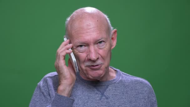 Närbild shoot av gamla Senior kaukasiska man som har ett telefonsamtal tittar på kamera med bakgrund isolerade på grön — Stockvideo