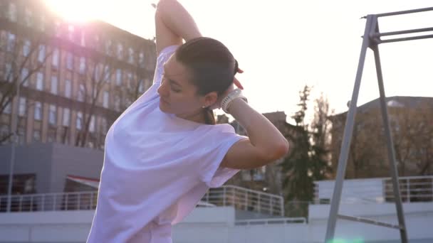 Primer plano retrato de joven atractivo ajuste caucásico hembra estiramiento y preparación para el entrenamiento al aire libre en el estadio — Vídeo de stock