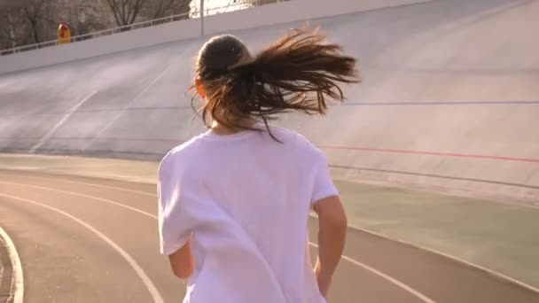 Primer plano vista trasera retrato de joven atractivo ajuste caucásico hembra con cola de caballo corriendo al aire libre en el estadio en la ciudad urbana — Vídeos de Stock