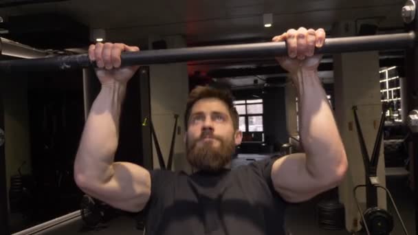 Tiro close-up de musculoso adulto fisiculturista atlético levantando-se nas barras dentro de casa no ginásio — Vídeo de Stock