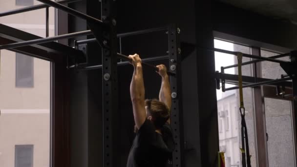 Närbild sidovy shoot of Adult muskulös atletisk bodybuilder utbildning och lyfta sig själv på barerna inomhus i gymmet — Stockvideo