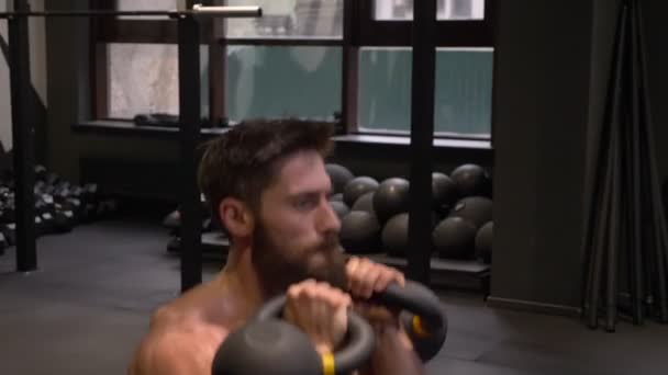 Gros plan pousse de l'homme sportif musclé adulte faisant squats avec les kettlebells à l'intérieur dans la salle de gym — Video