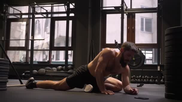Closeup shoot of adult muscular athletic shirtless man stretching after workout indoors in the gym — Stock Video