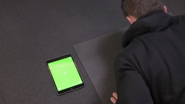 Close-up shoot van volwassen gespierde atletische man duwen met de Tablet met groene Chroma scherm liggend naast binnen in de sportschool — Stockvideo
