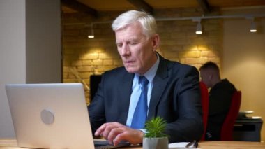 İşyerinde ofiste ki dizüstü bilgisayarı kullanan eski beyaz işadamının yakın çekim çekimi