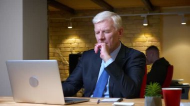 İşyerinde ofiste ki dizüstü bilgisayarı kullanan eski kafkasyalı meşgul işadamının yakın çekim çekimi