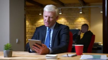 Eski kafkas işadamının tableti kullanarak ve işyerinde ofiste ki kapalı mekanlarda kameraya yeşil ekran göstermesinin yakın çekim çekimi