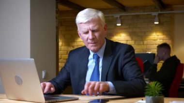 Eski kafkas işadamının dizüstü bilgisayar kullanarak telefonla bir bildirim alma ve işyerinde ofiste kapalı kutlama mutlu olmak yakın çekim