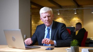 Eski kafkas işadamının dizüstü bilgisayarı kullanarak telefonla bildirim de aldığı ve işyerinde ki ofiste mutsuz olması nın yakın çekim çekimi