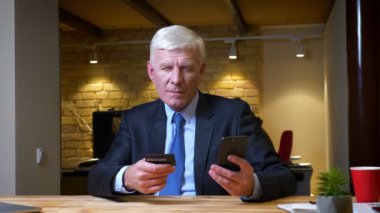 İşyerinde ofis içinde telefon ve kredi kartı kullanarak online alışveriş eski kafkas işadamı closeup çekim