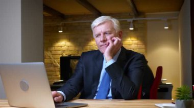 İşyerinde ki ofiste ki kapalı mekanlarda sıkılmış ve rahatsız olan dizüstü bilgisayarı kullanan eski beyaz işadamının yakın çekim çekimi