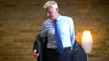 Eski beyaz işadamının ceketini çıkarıp dairede kapalı mekanda işten sonra kanepede oturan televizyonu izlediği yakın çekim portresi