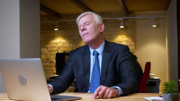 Closeup shoot of old caucasian businessman using the laptop being bored indoors in the office on the workplace — Stock Video