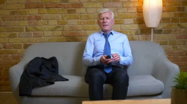Eski kafkas işadamının dairede kapalı mekanda işten sonra kanepede oturan tv izlerken yakın çekim portresi