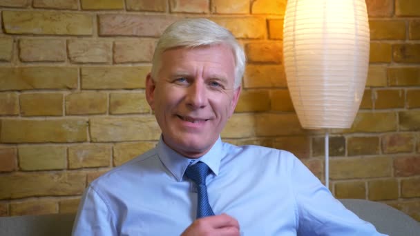 Closeup portrait of old caucasian businessman looking at camera and smiling happily being at home after work indoors in a cozy apartment — Stock Video