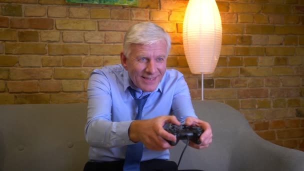 Retrato de close-up do velho homem de negócios caucasiano jogando videogames e ganhando ser feliz comemorando sentado no sofá dentro de casa no apartamento — Vídeo de Stock