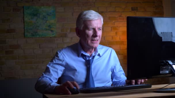 Closeup portrait of old caucasian businessman playing video games on the computer winning and being happy indoors in the apartment with lights off — Stock Video