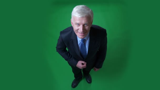 Closeup top shoot view of old caucasian businessman in a suit smiling happily and looking at camera with background isolated on green — Stock Video