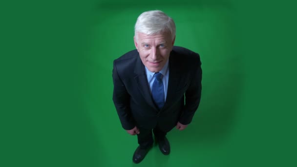 Closeup top shoot vista de velho empresário caucasiano em um terno mostrando um polegar para cima olhando para a câmera com fundo isolado em verde — Vídeo de Stock
