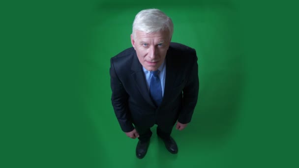緑色に隔離された背景を持つカメラを見てスーツを着た古い白人ビジネスマンのクローズアップトップシュートビュー — ストック動画
