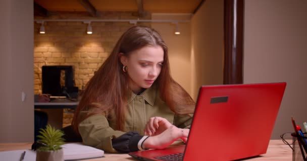 Portrait de jeune adolescente travaillant avec un ordinateur portable étant optimiste et positive au bureau . — Video