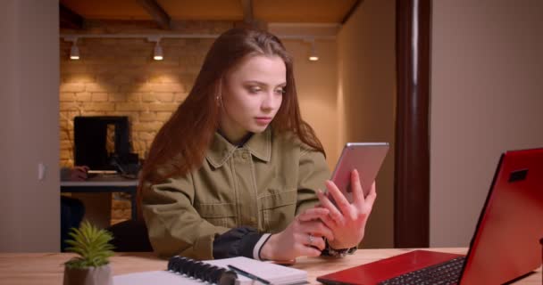 Портрет молодой девушки-подростка, работающей с планшетом, показывает его зеленый хроматический экран на камеру в офисе . — стоковое видео