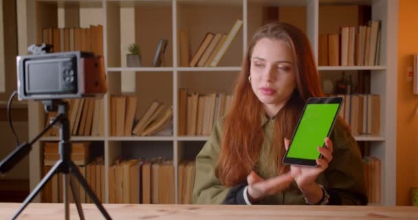女性 Vlogger 在书架背景上将 Tabet 的绿色色度屏幕显示为摄像机. — 图库视频影像