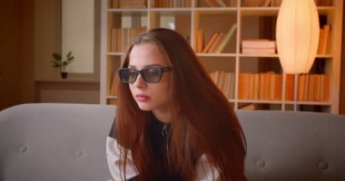 3d gözlükgenç genç kız Portresi evde kitaplıklar arka plan kanepede oturan Tv'de film izler.