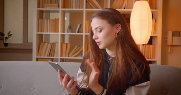 Genç bayan blogcu uygulamayı tablette açıyor ve evdeki kitaplıklarda yeşil renk ekranını gösteriyor. — Stok video