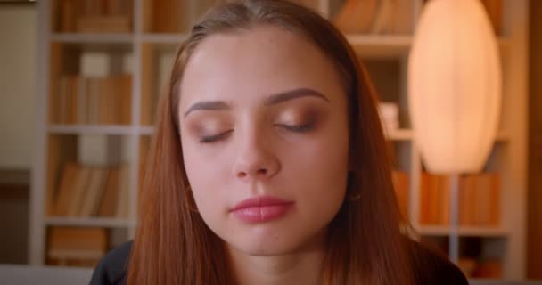 Gros plan portrait de jeunes étudiantes regarde attentivement dans la caméra et sourit sur fond de bibliothèque . — Video