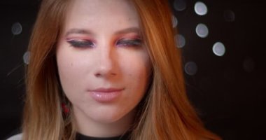 Bulanık ışıklar bokeh arka plan üzerinde ışık gülümseme ile kamera içine olağanüstü parlak makyaj saatler ile Blonde modeli.