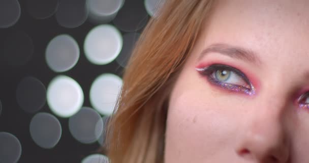 Potret setengah wajah dari model pirang cantik dengan make-up cerah menonton ke atas yang bermimpi pada latar belakang bokeh . — Stok Video