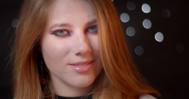 Modello di zenzero con straordinari brillanti sorrisi make-up in fotocamera essere calmo su luci sfocate sfondo bokeh . — Video Stock