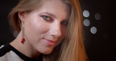 Parlak makyaj ile seksi zencefil modeli bulanık ışıklar bokeh arka plan üzerinde onunla flört kamera içine gülümseyen.