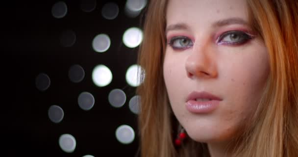 Profilshooting des Ingwer-Models mit modernem Make-up wendet sich der Kamera zu und lächelt gelassen auf Bokeh-Hintergrund. — Stockvideo