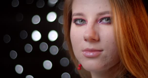 Filmagem de perfil do modelo de gengibre com maquiagem legal se transforma em câmera e relógios sedutoramente no fundo bokeh . — Vídeo de Stock
