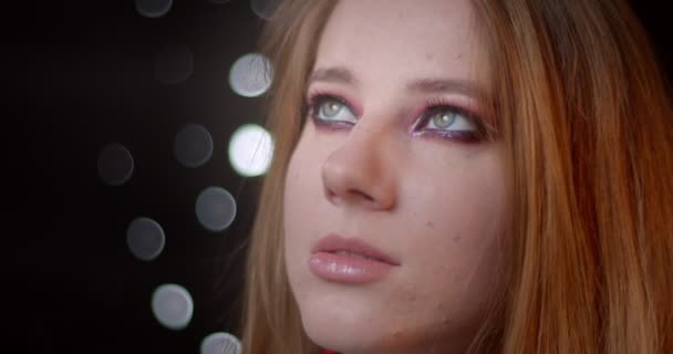 Retrato de modelo rubia bonita con maquillaje brillante mirando hacia arriba siendo soñador sobre fondo bokeh . — Vídeos de Stock