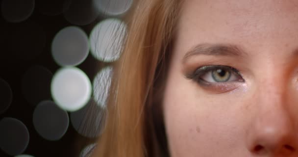 Närbild halv ansikts tagning av blond modell med extraordinära mörka och blanka smink på suddiga lampor bokeh bakgrund. — Stockvideo