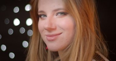 Bokeh arka planda güzel bir gülümseme ile kameraya glitter koyu makyaj saatler ile Çarpıcı sarışın modeli.