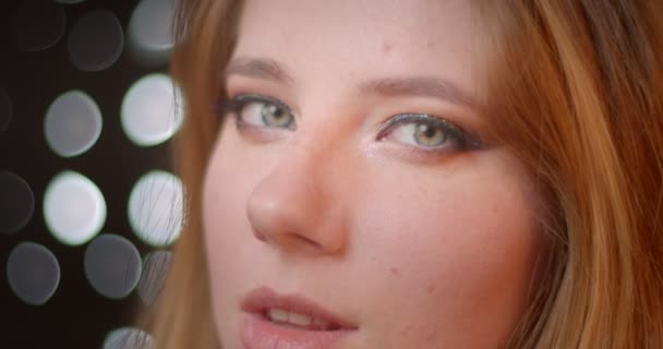 Sexy blonďatý model s živými a lesklými hodinkami na kameru s koketním pohledem na pozadí bokeh. — Stock video