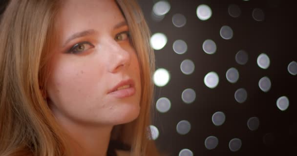 Profile shoot of blonde model with glitter make-up smiles seducing the camera on bokeh background. — Stock Video