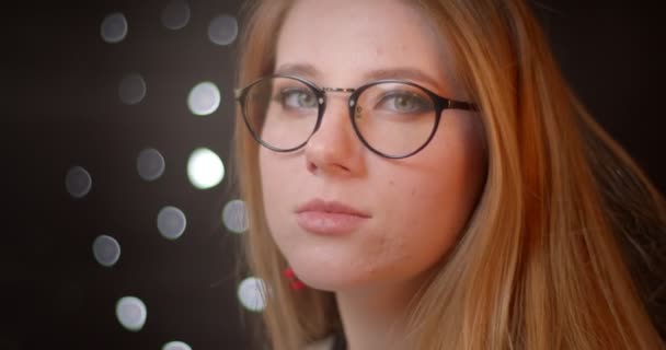 Profilo tiro di modello bionda in occhiali con luminoso make-up si trasforma in macchina fotografica e sorride felicemente su sfondo bokeh . — Video Stock