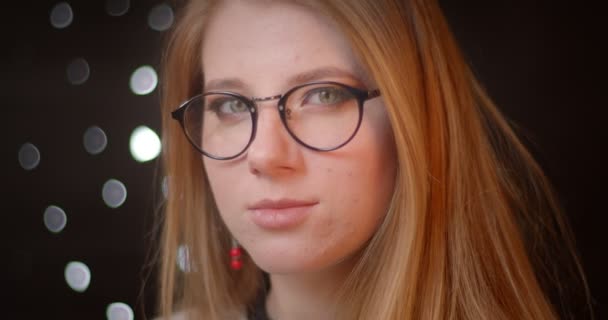 Profile shoot of blonde model in glasses with bright make-up turns to camera and smiles prettily on bokeh background. — Stock Video