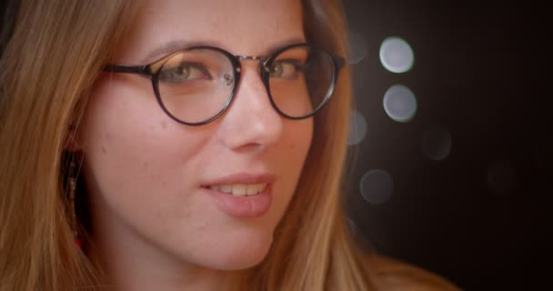 Blondes Model mit grellem Make-up in Brille schaut verführerisch in die Kamera auf Bokeh-Hintergrund. — Stockvideo