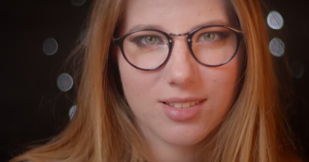 Blondes Model mit grellem Make-up in Brille schaut verträumt in die Kamera auf Bokeh-Hintergrund. — Stockvideo