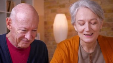 İki üst düzey gri saçlı kafkas eşlerinin dizüstü bilgisayarda görüntülü sohbet konuşurken yakın çekim portresi ofiste memnun olmak.