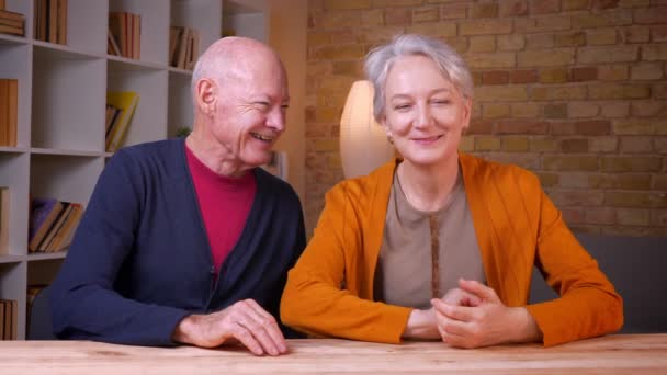 Senior Kaukasische echt genoten praten met elkaar kijken aangenaam in de camera zittend thuis. — Stockvideo