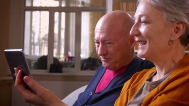 Üst düzey kafkas eşlerin yakın çekim rahat evde tablet arkadaşları ile online videochat konuşmak.