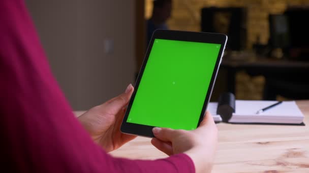 Γυναικεία χέρια που κρατούν κάθετα tablet με πράσινη οθόνη αποχρώσεων στο γραφείο. — Αρχείο Βίντεο